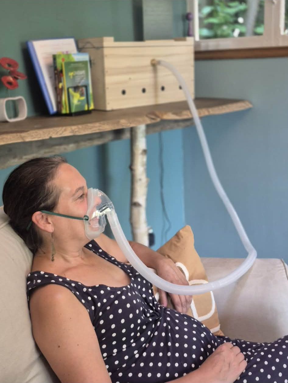 Femme installée dans un fauteuil respirant l'air des ruches avec un masque d'inhalation individuel